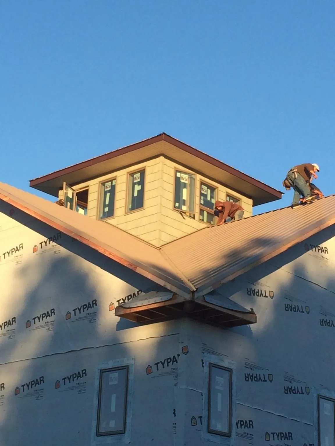 Roofers working around a rooftop cupola on a new metal roof at sunset — Roof Waterproofing in Buffalo by Roofing Brothers